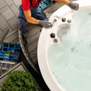 Técnico realizando el mantenimiento del panel de control de un jacuzzi con herramientas a su lado.