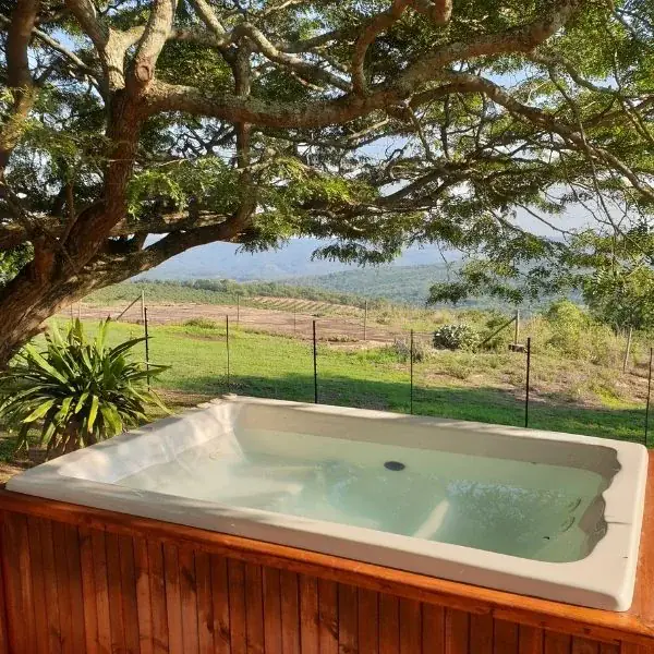 jacuzzi exterior revestido de madera bajo un árbol con vistas panorámicas a la montaña.